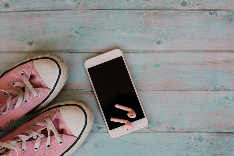 pink sneakers, smart phone and headphones on blue background sport concept