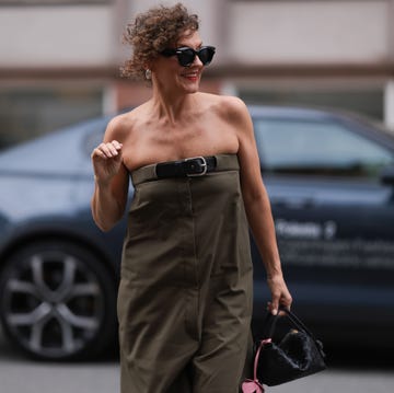 pintalabios labios rojos mujer una mujer camina por la calle con unas voluminosas gafas de sol de loewe, los labios pintados de rojo y un traje verde oliva sin tirantes