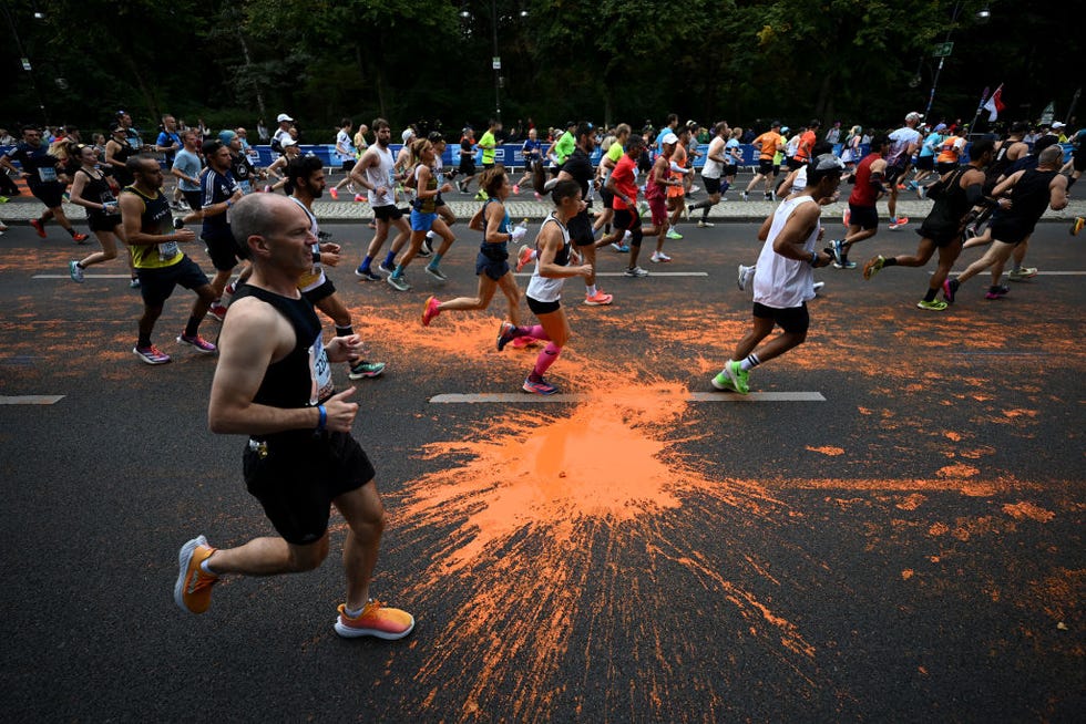 varios participantes en el maratón de berlín pasan junto a la pintura arrojada por activistas