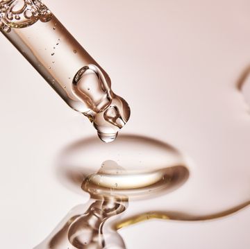 a pipette with a drop of serum on a beige background
