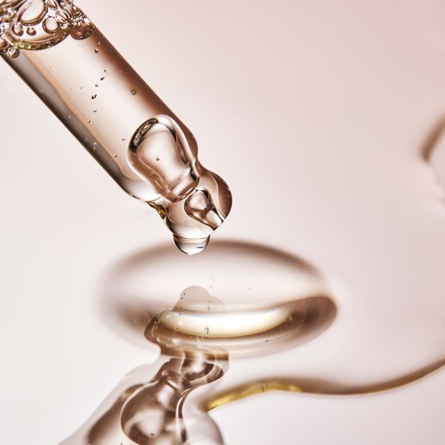a pipette with a drop of serum on a beige background