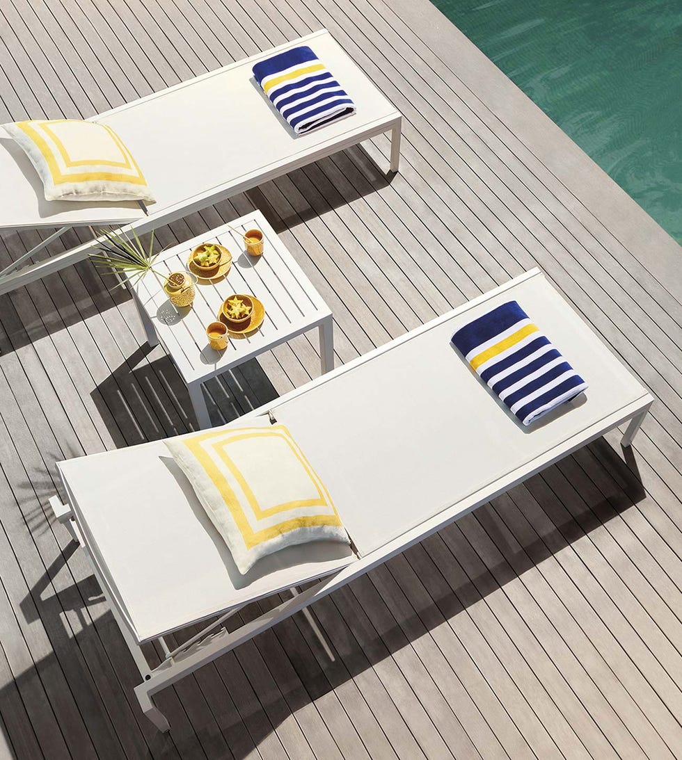 piscina con suelo de madera y tumbonas blancas