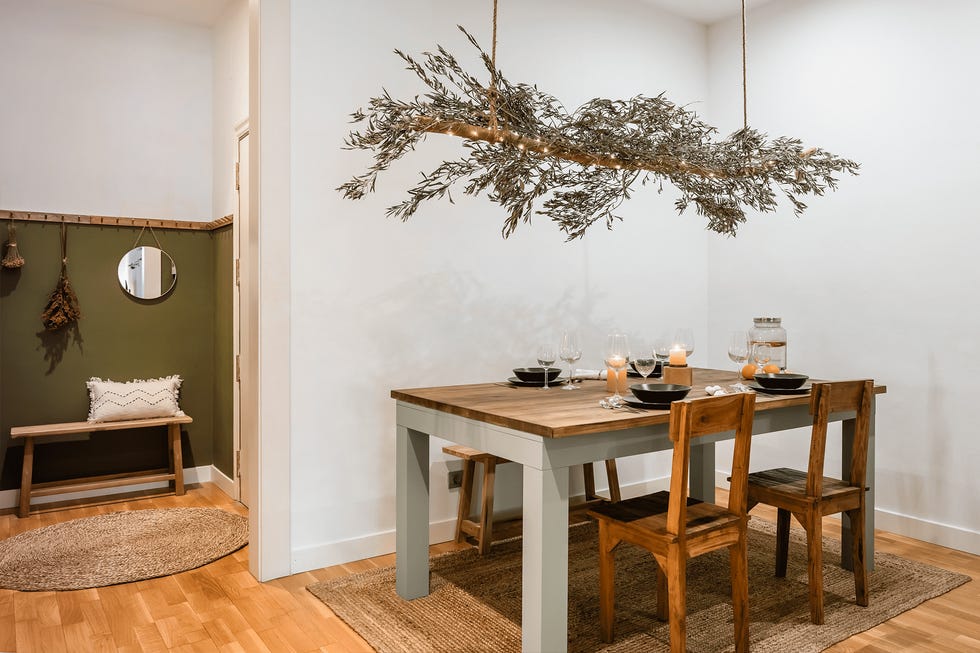 comedor rústico con mesa y sillas de madera y tronco con ramas de olivo secas