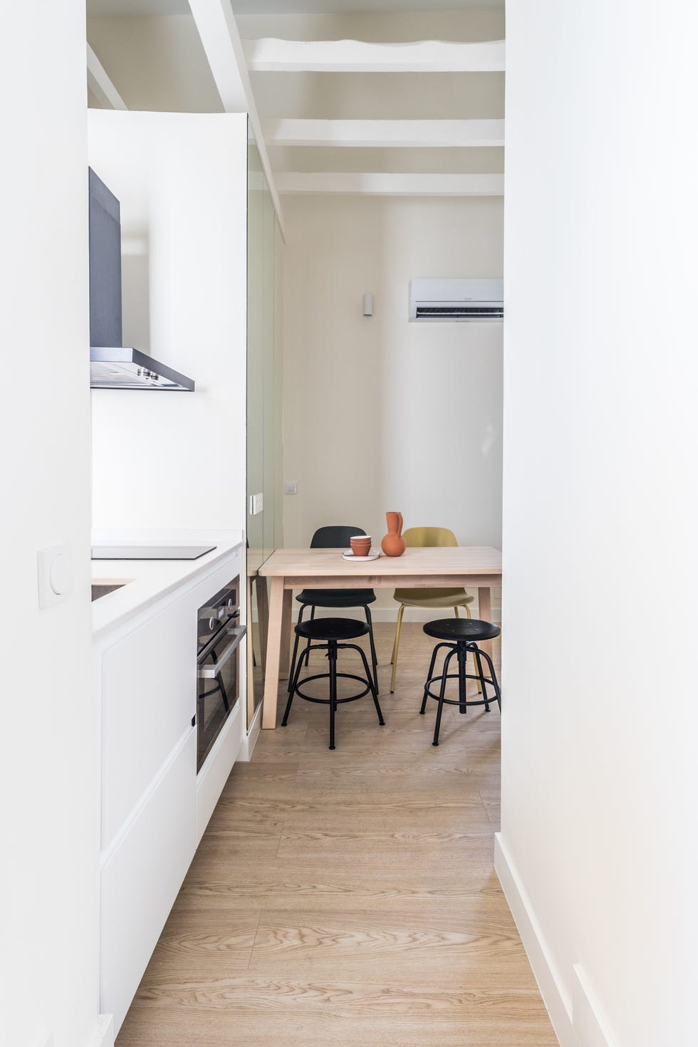cocina blanca moderna y comedor con mesa de madera clara