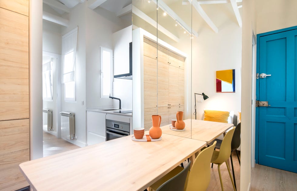 salón, comedor y cocina de diseño moderno con muebles de madera clara y pared de espejo
