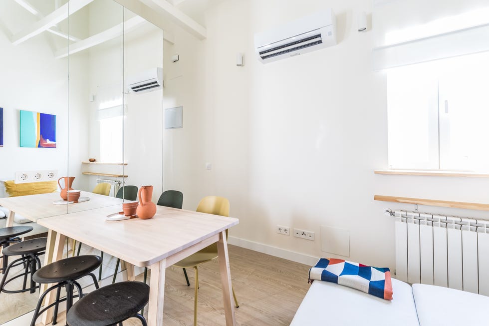 salón, comedor y cocina de diseño moderno con muebles de madera clara y pared de espejo