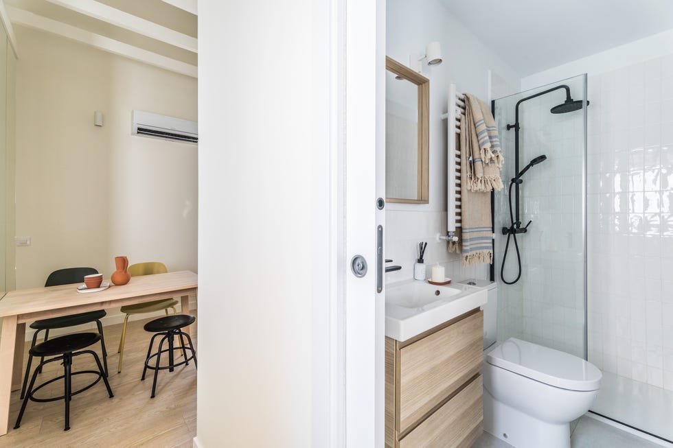 baño con puerta corredera, mueble bajo lavabo de madera suspendido y ducha
