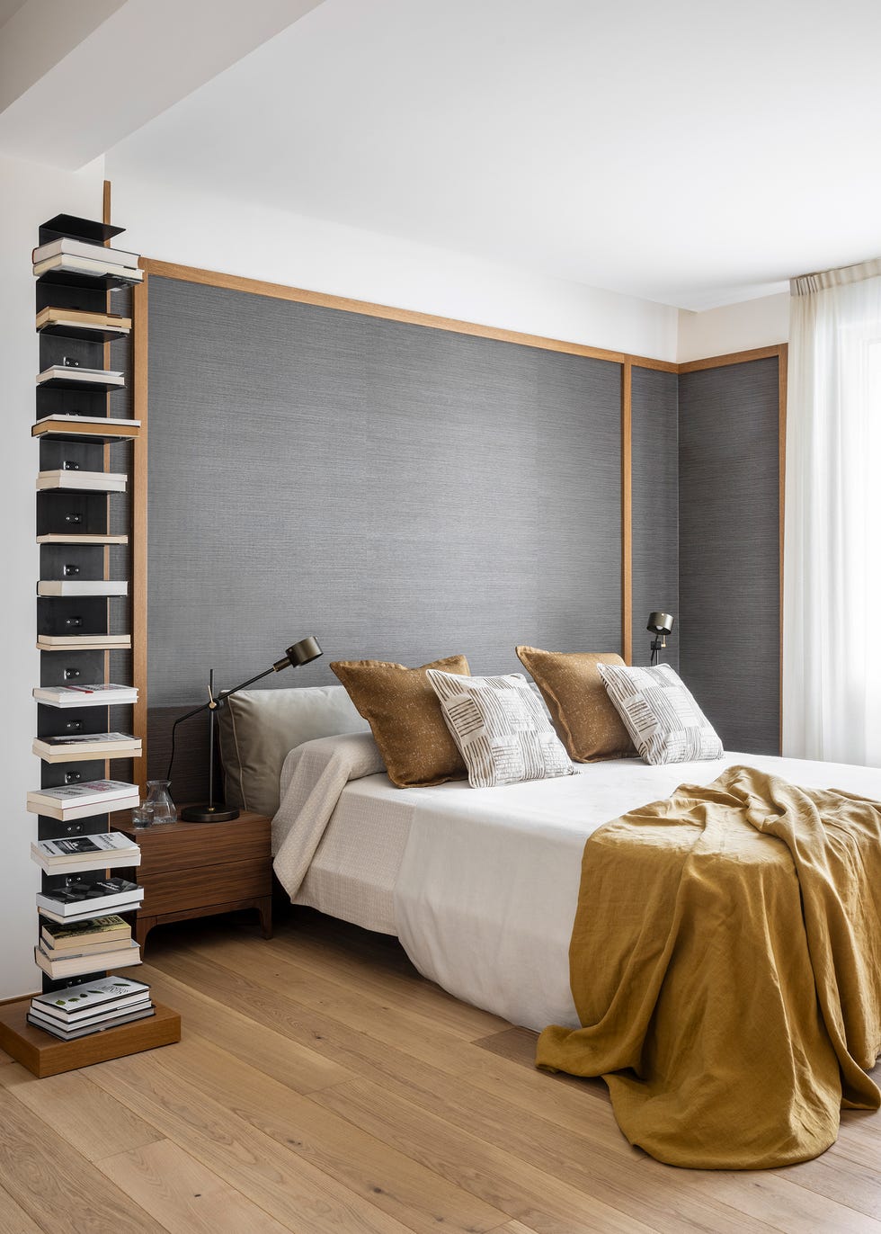 dormitorio con estantería para libros y pared del cabecero con papel texturizado gris