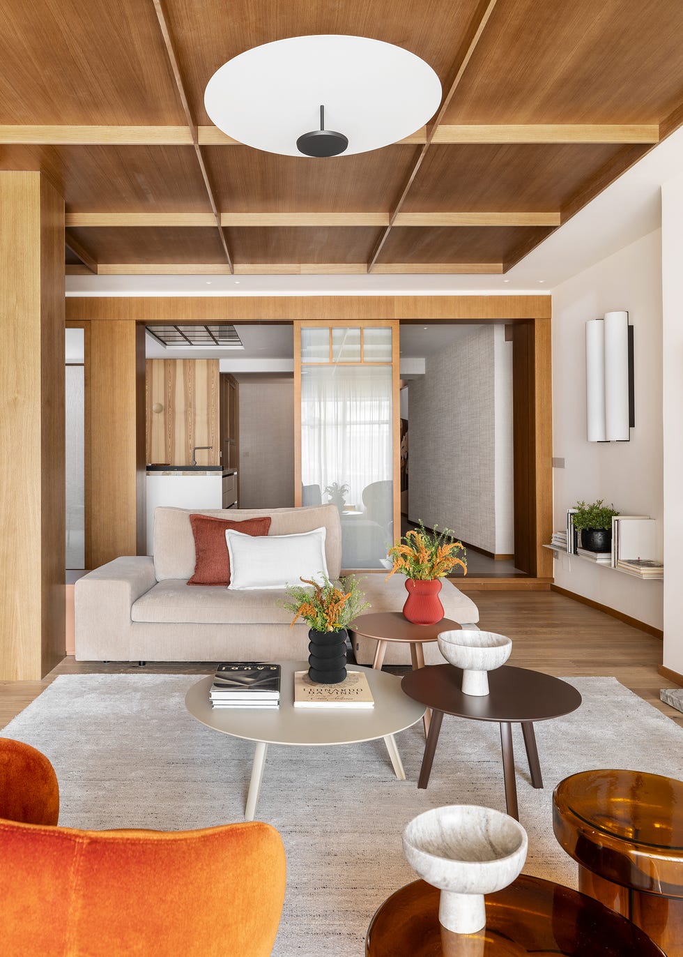 salón con techo y pilares de madera, sofá beige y mesas de centro tipo nido