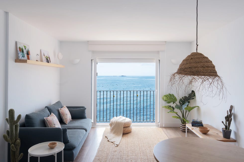 salón de estilo playero con sofá azul, mesa de centro de madera y alfombra de fibras