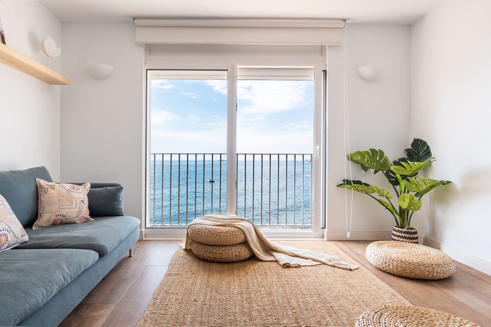 salón de estilo playero con sofá azul, pufs y alfombra de fibras