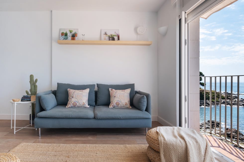 salón de estilo playero con sofá azul, mesa auxiliar, pufs y alfombra de fibras