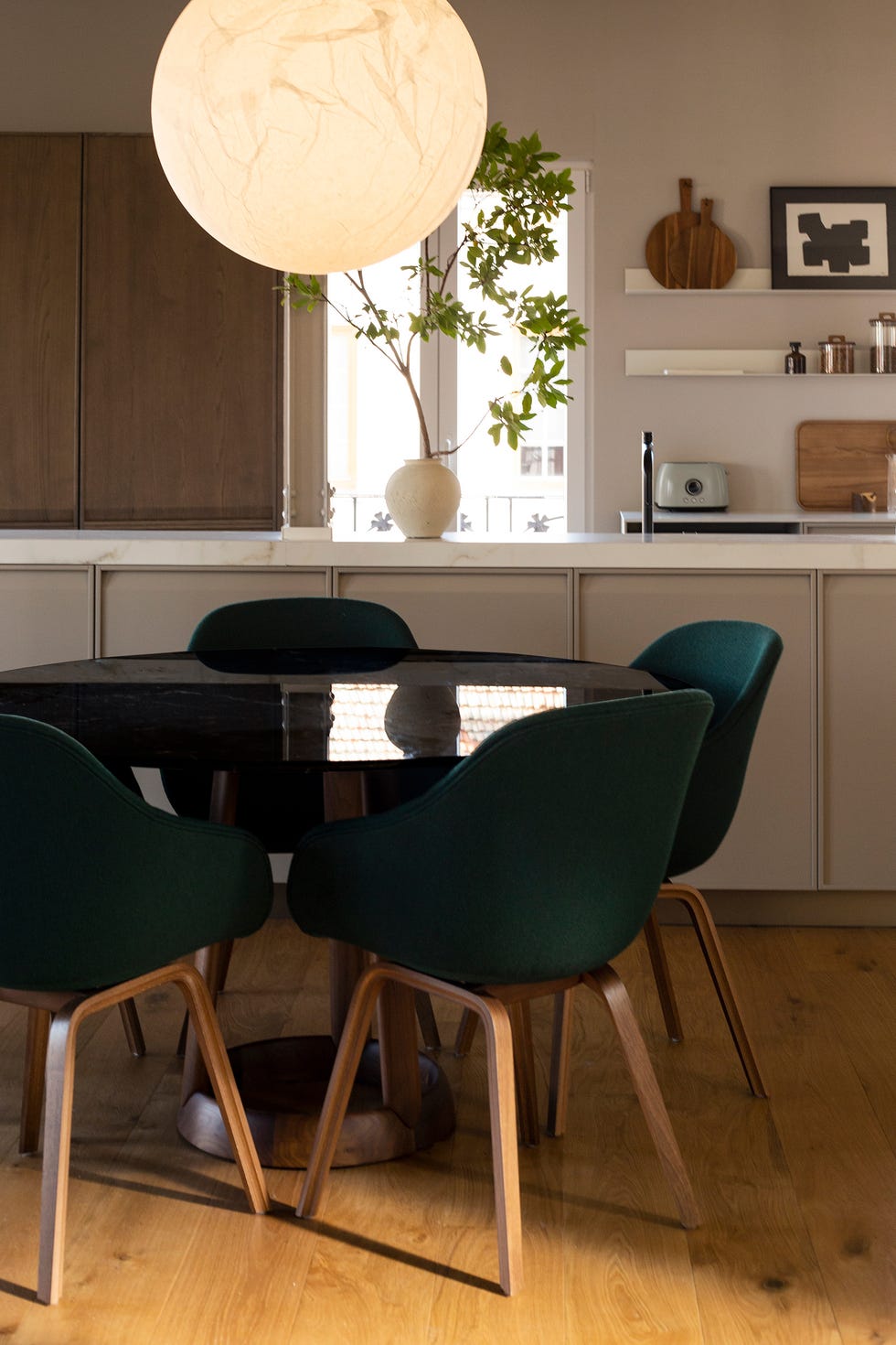 mesa de comedor redonda de mármol negro con sillas tapizadas en verde