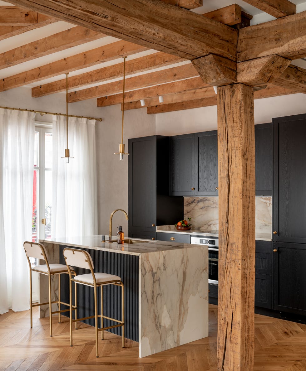 cocina abierta con isla central de mármol y armarios con puertas negras de madera