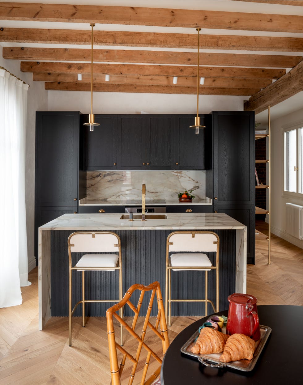cocina abierta con isla central de mármol y armarios con puertas negras de madera