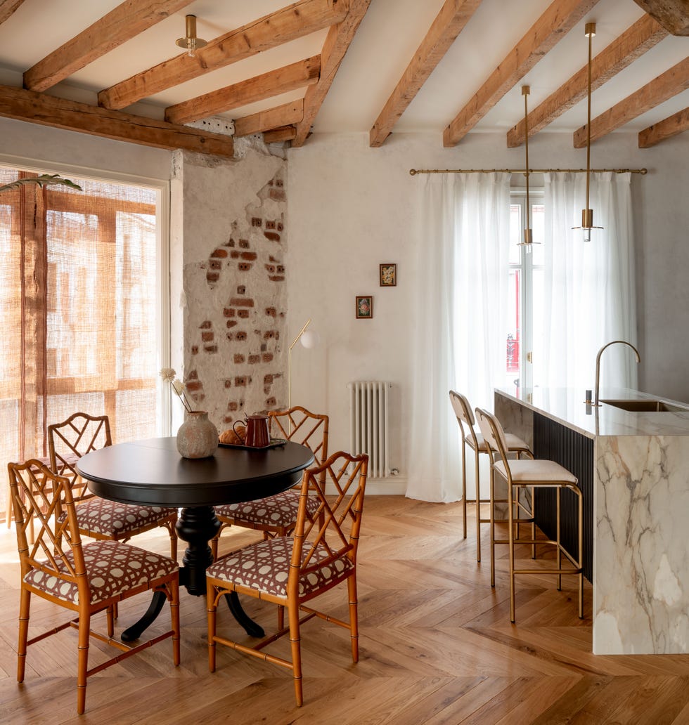 comedor y cocina con vigas vistas de madera, paredes de piedra y muebles vintage