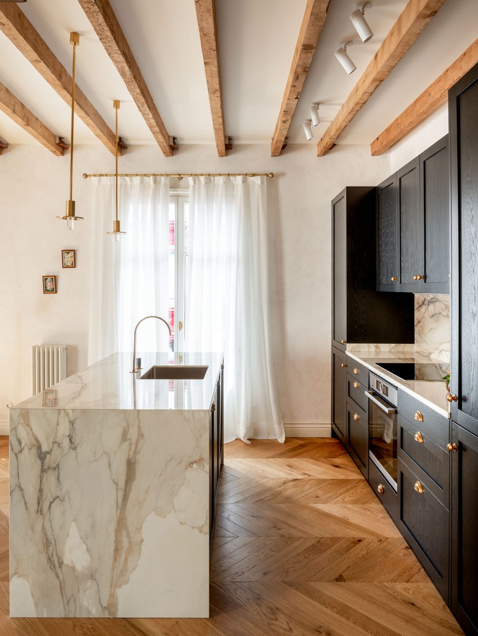 cocina abierta con isla central de mármol y armarios con puertas negras de madera