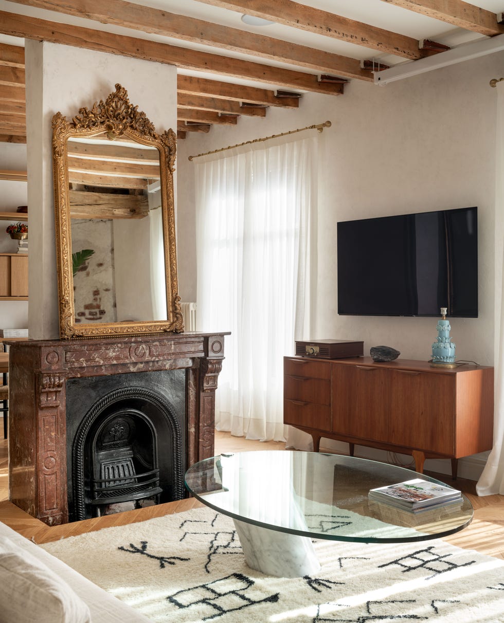 salón con vigas vistas de madera y chimenea de mármol