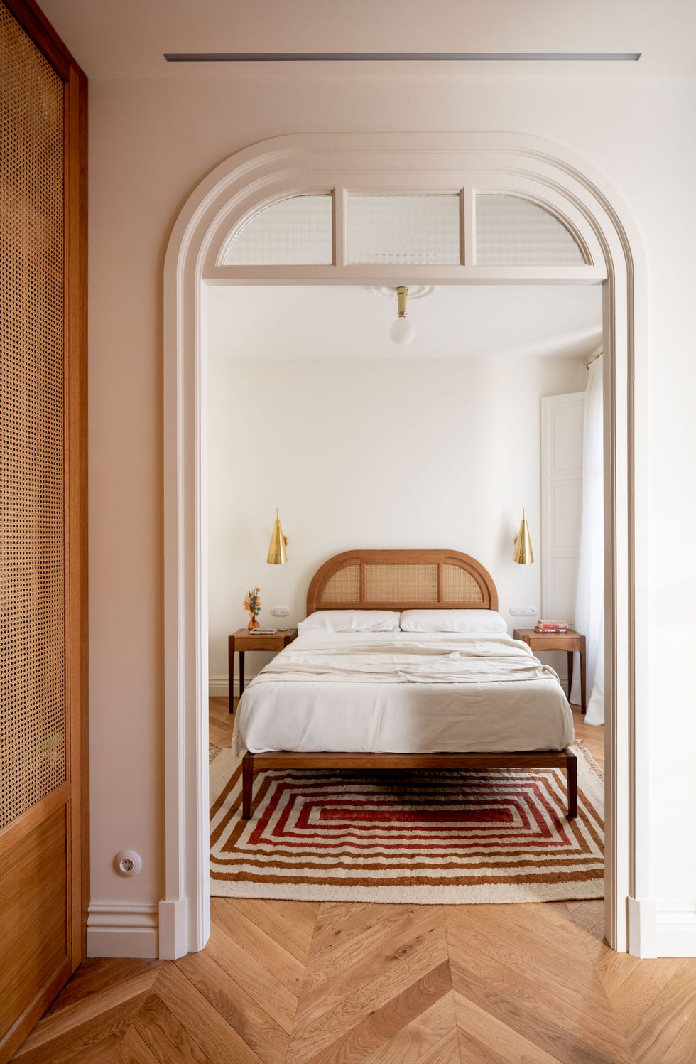 cama con cabecero de rejilla de ratán y apliques dorados