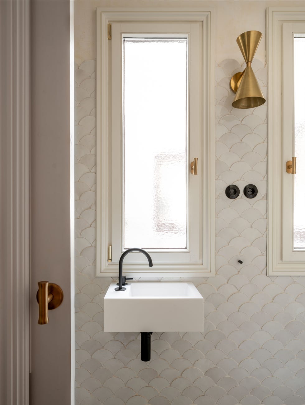 baño con azulejos blancos en escama y grifo negro mate