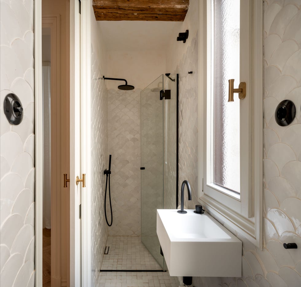 baño con azulejos blancos en escama, ducha a ras de suelo y grifería negro mate