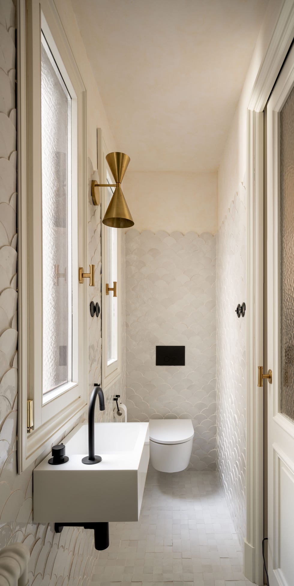baño con azulejos blancos en escama y grifo negro mate en lavabo suspendido