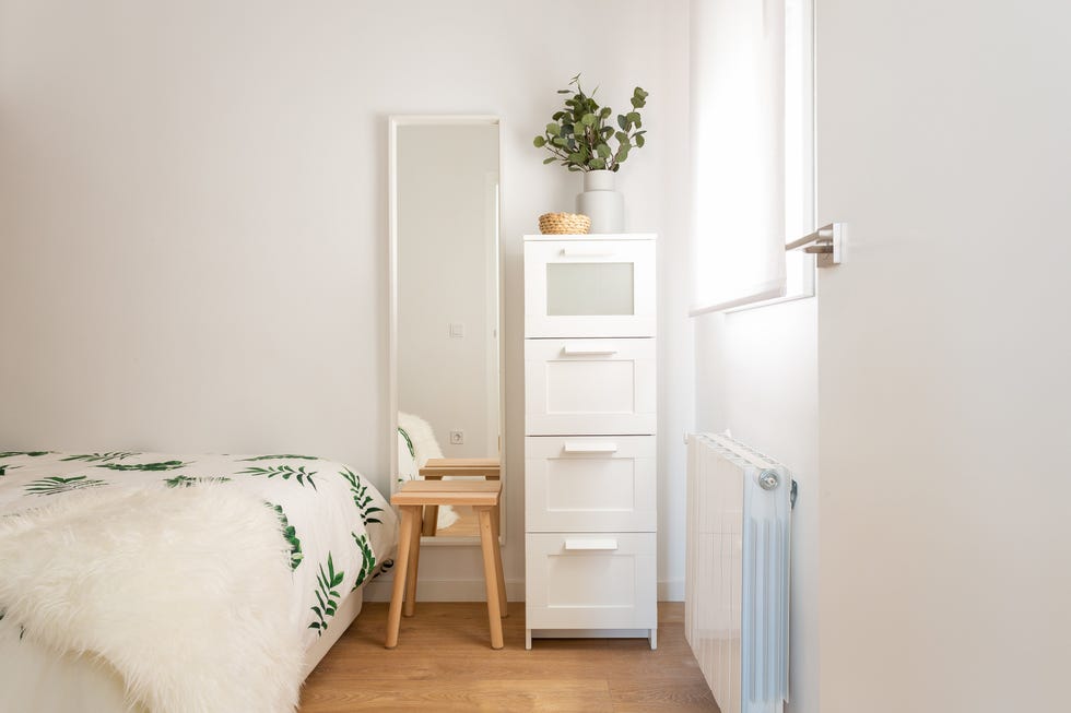 espejo de pared, taburete de madera y estantería blanca