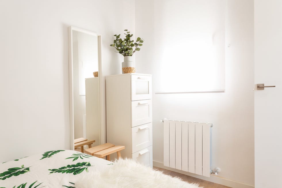 espejo de pared, taburete de madera y estantería blanca
