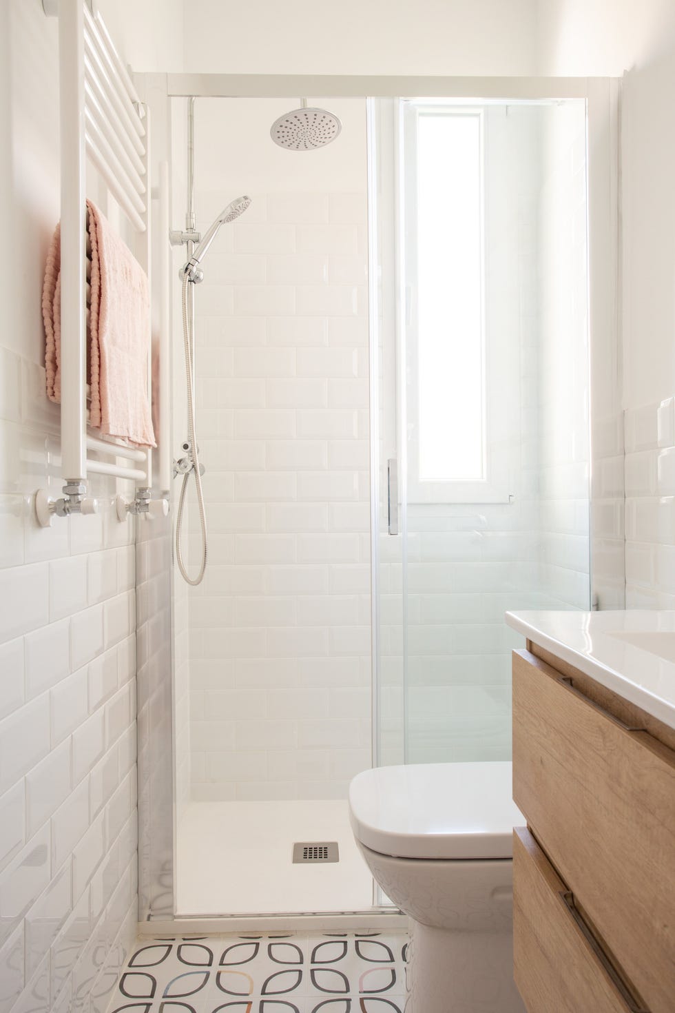 baño con mueble volado de madera, azulejos blancos tipo metro y baldosas con diseño geométrico