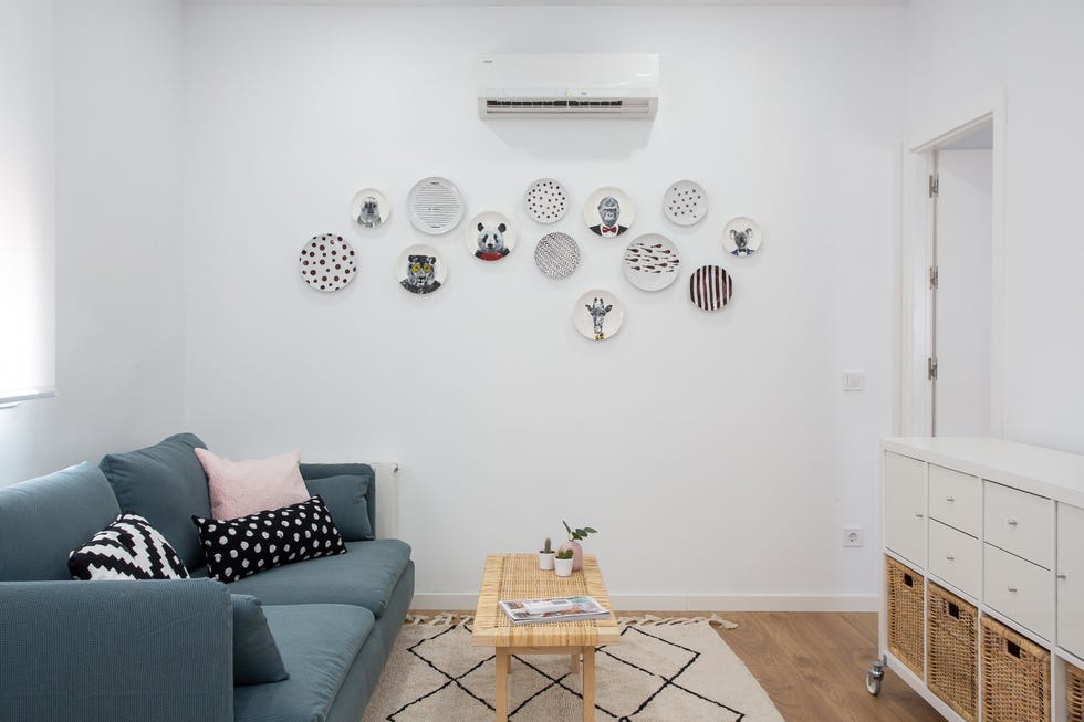 salón nórdico con sofá azul, mesa de centro de fibras, estantería blanca y platos decorativos