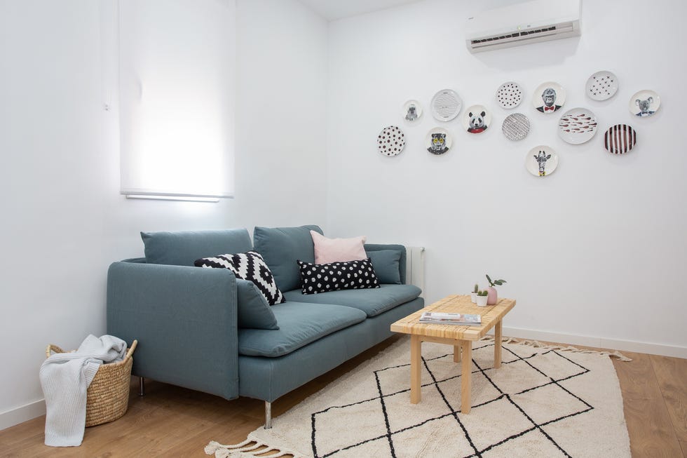 salón nórdico con sofá azul, mesa de centro de fibras y platos decorativos
