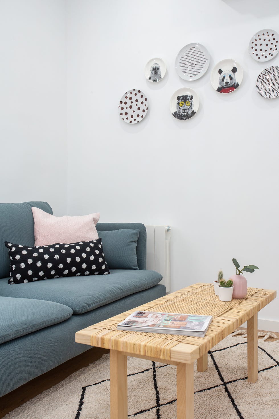 salón nórdico con sofá azul, mesa de centro de fibras y platos decorativos