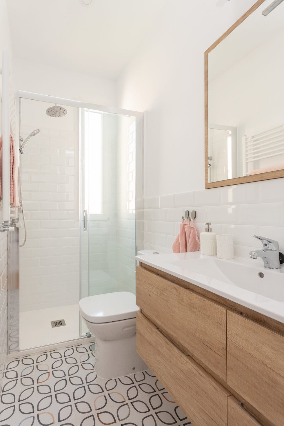 baño con mueble volado de madera, azulejos blancos tipo metro y baldosas con diseño geométrico