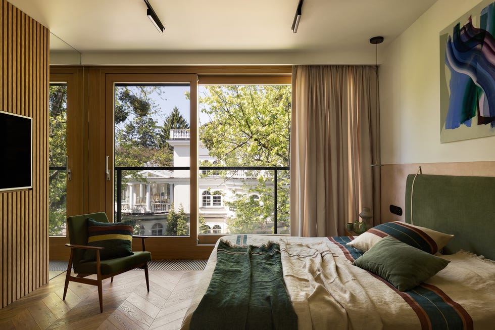 dormitorio con cabecero de terciopelo verde y puertas correderas con acceso a la terraza
