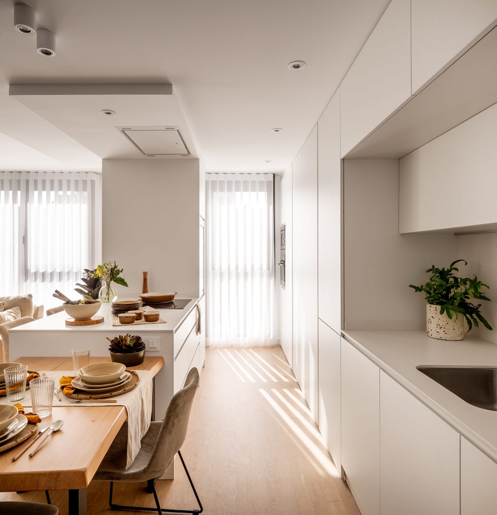 cocina abierta moderna en color blanco con isla y mesa de comedor anexa