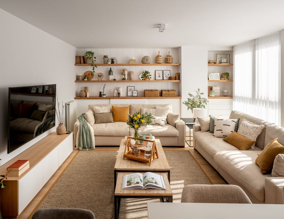 salón moderno con dos sofás de color beige, mesas de centro tipo nido y pared con tres estantes de madera