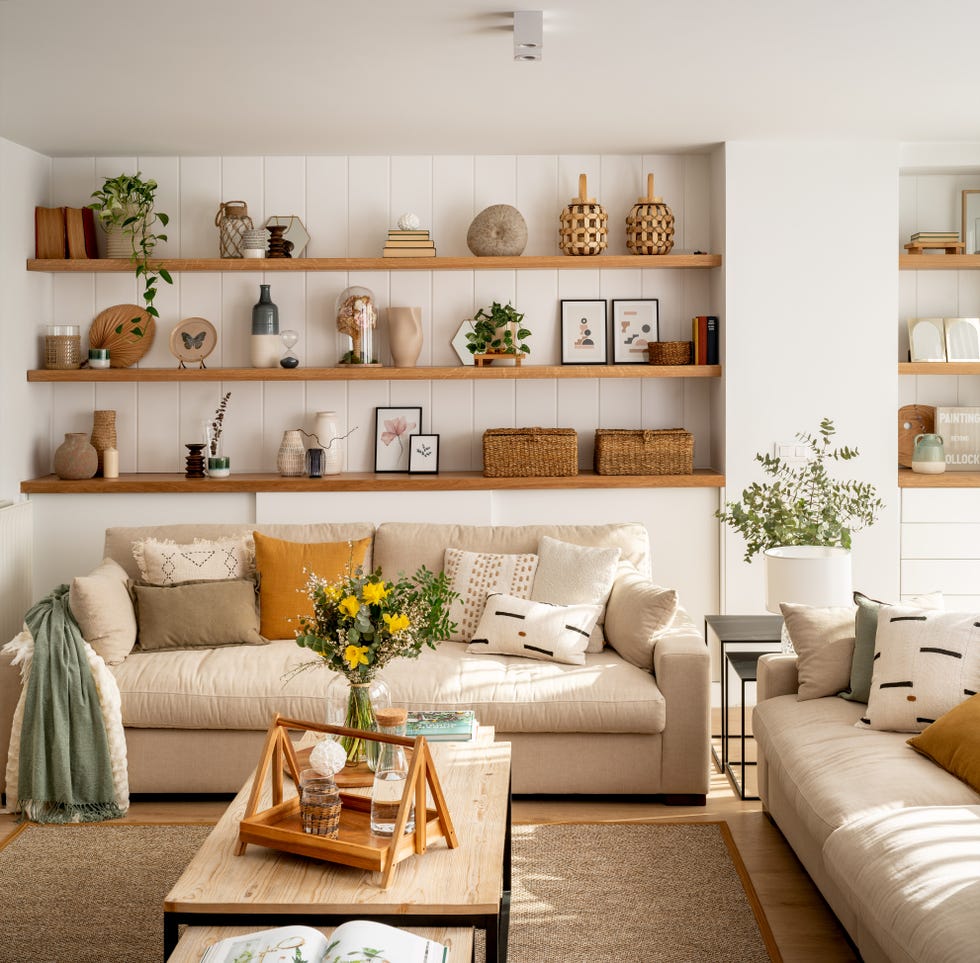 salón moderno con dos sofás de color beige, mesas de centro tipo nido y pared con tres estantes de madera