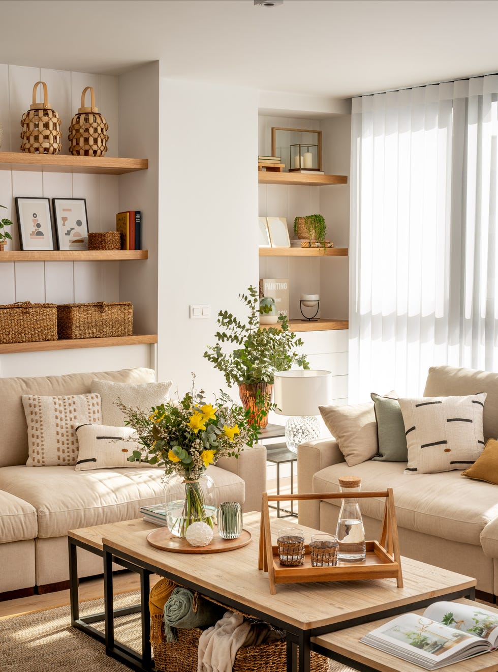 salón moderno con dos sofás de color beige, mesas de centro tipo nido y pared con tres estantes de madera