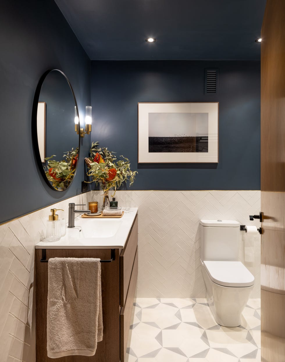 baño moderno con la pared pintada en azul oscuro y azulejos blancos en espiga