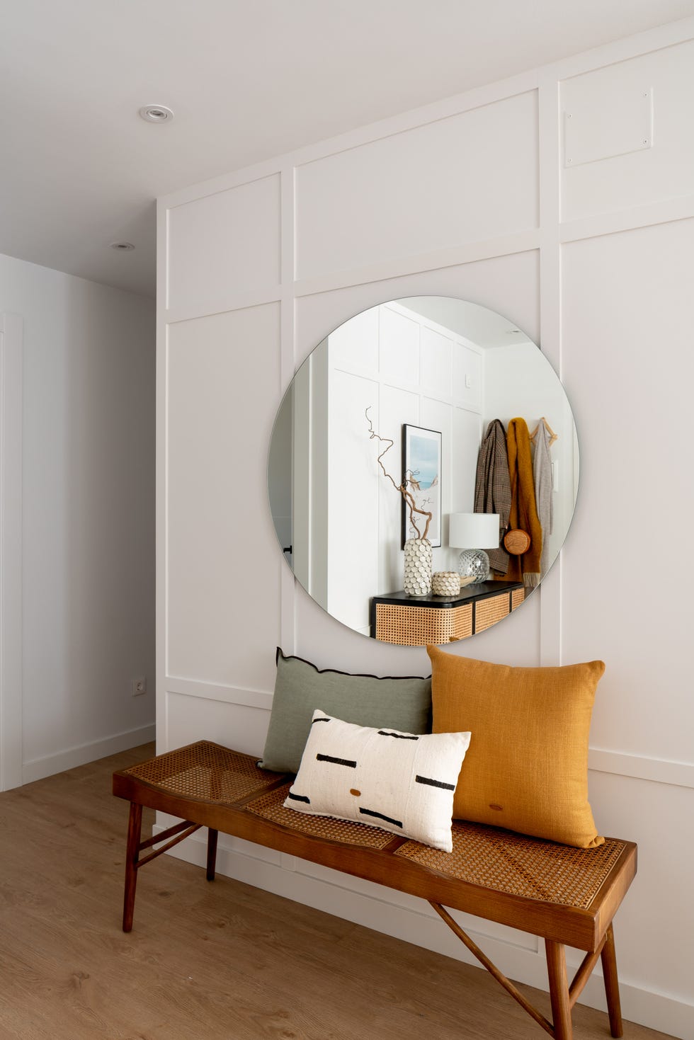 recibidor de estilo boho con banco de madera vintage y espejo redondo