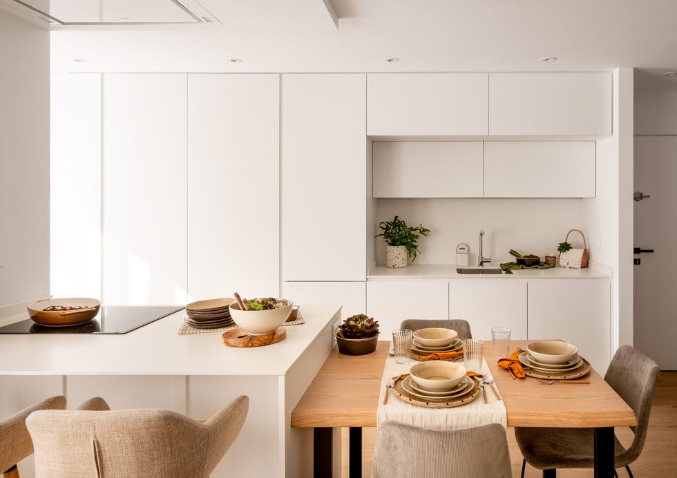 cocina abierta moderna en color blanco con isla y mesa de comedor anexa