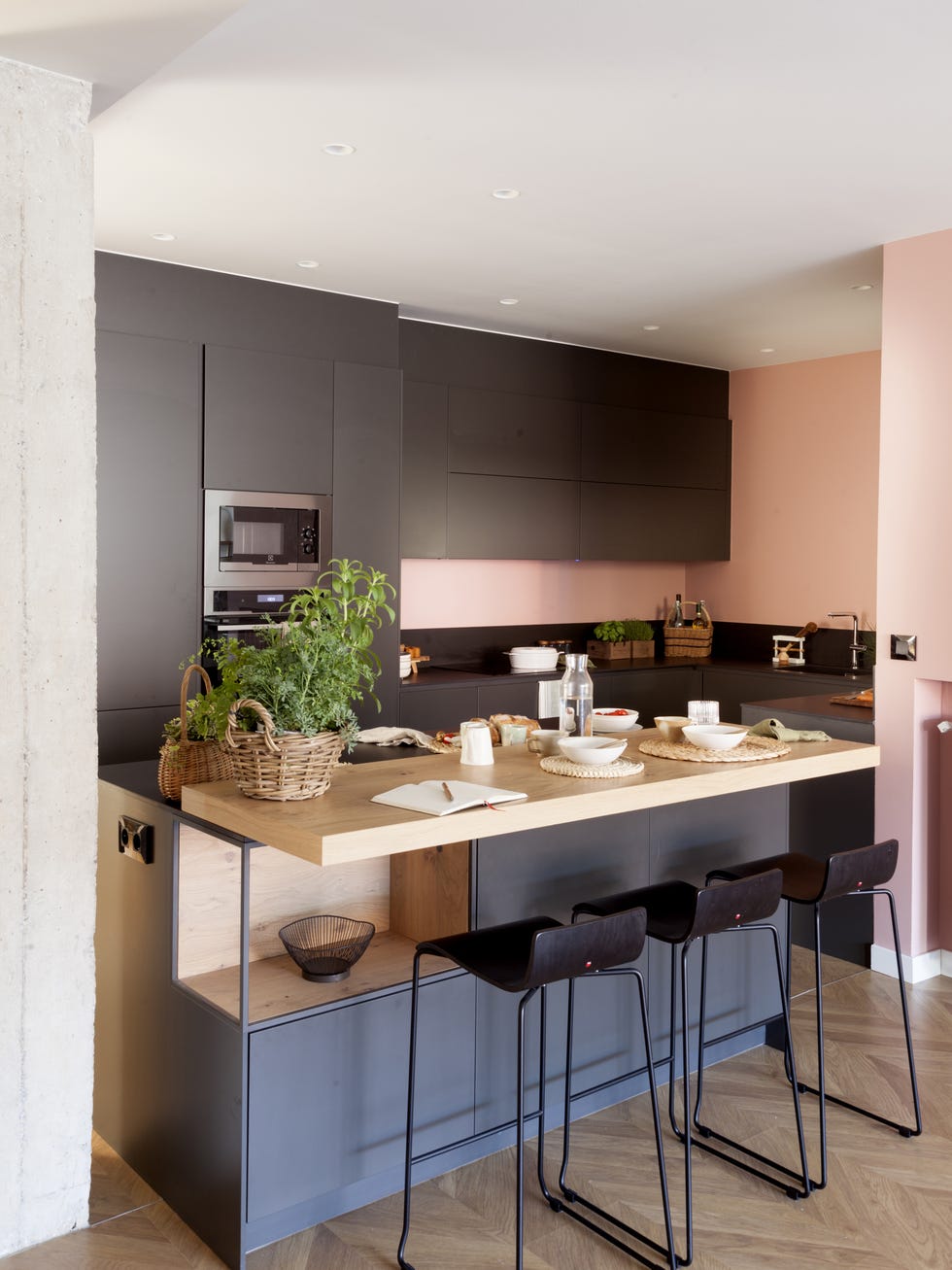 cocina moderna de color negro con isla central y pared rosa