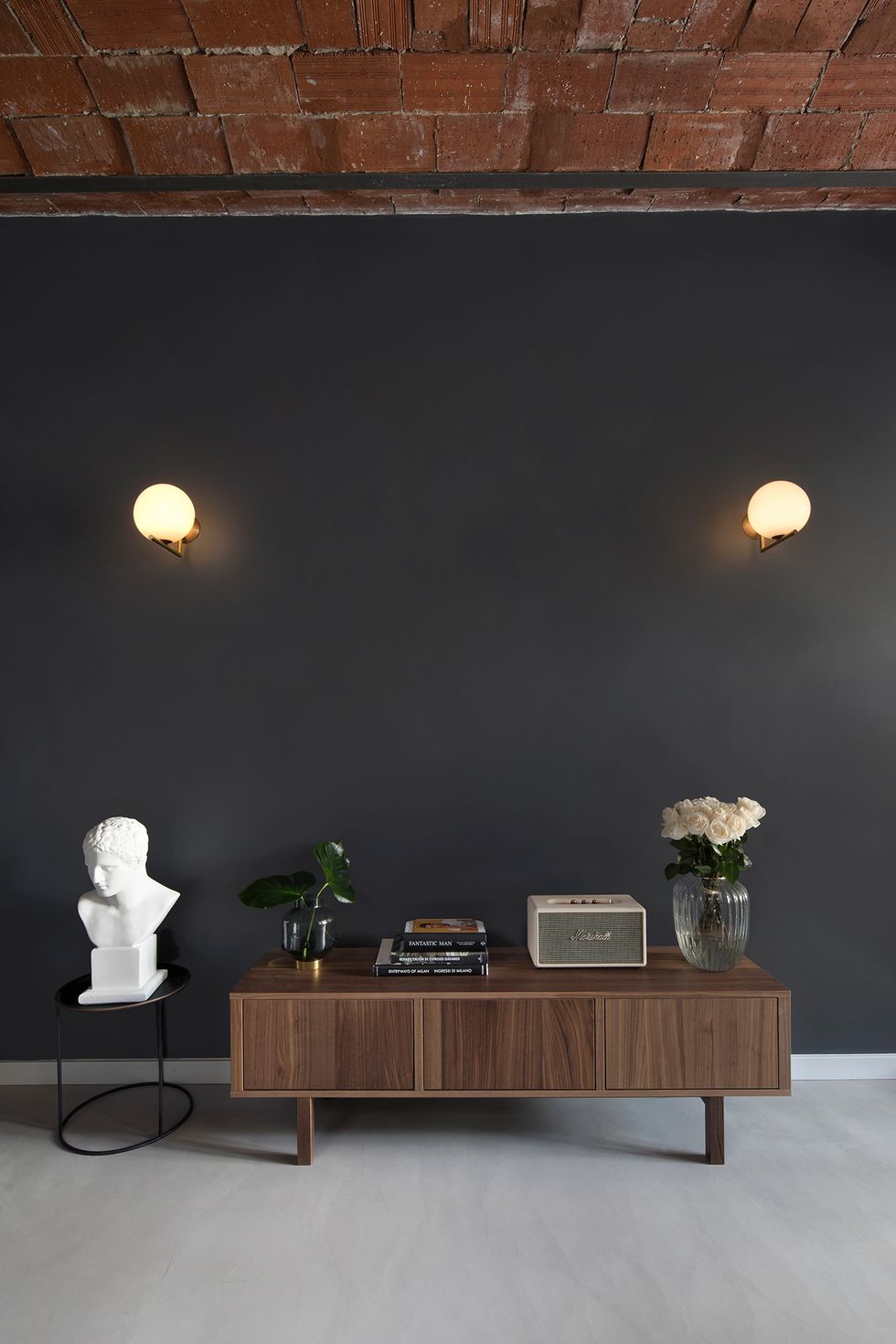 Aparador de madera con decoración vintage y lámparas de FLOS en la pared