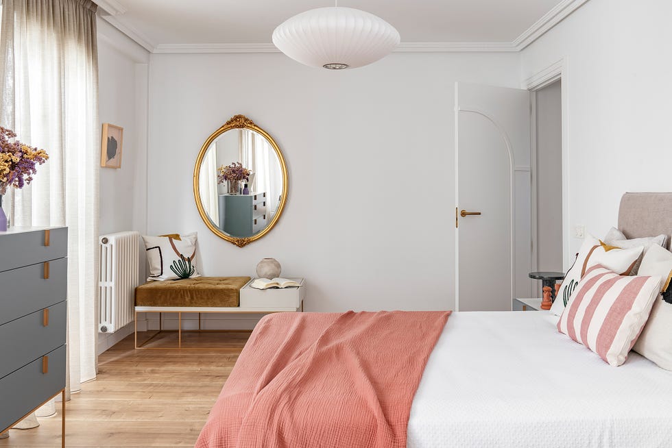 dormitorio con espejo de pared antiguo dorado y textiles rosas