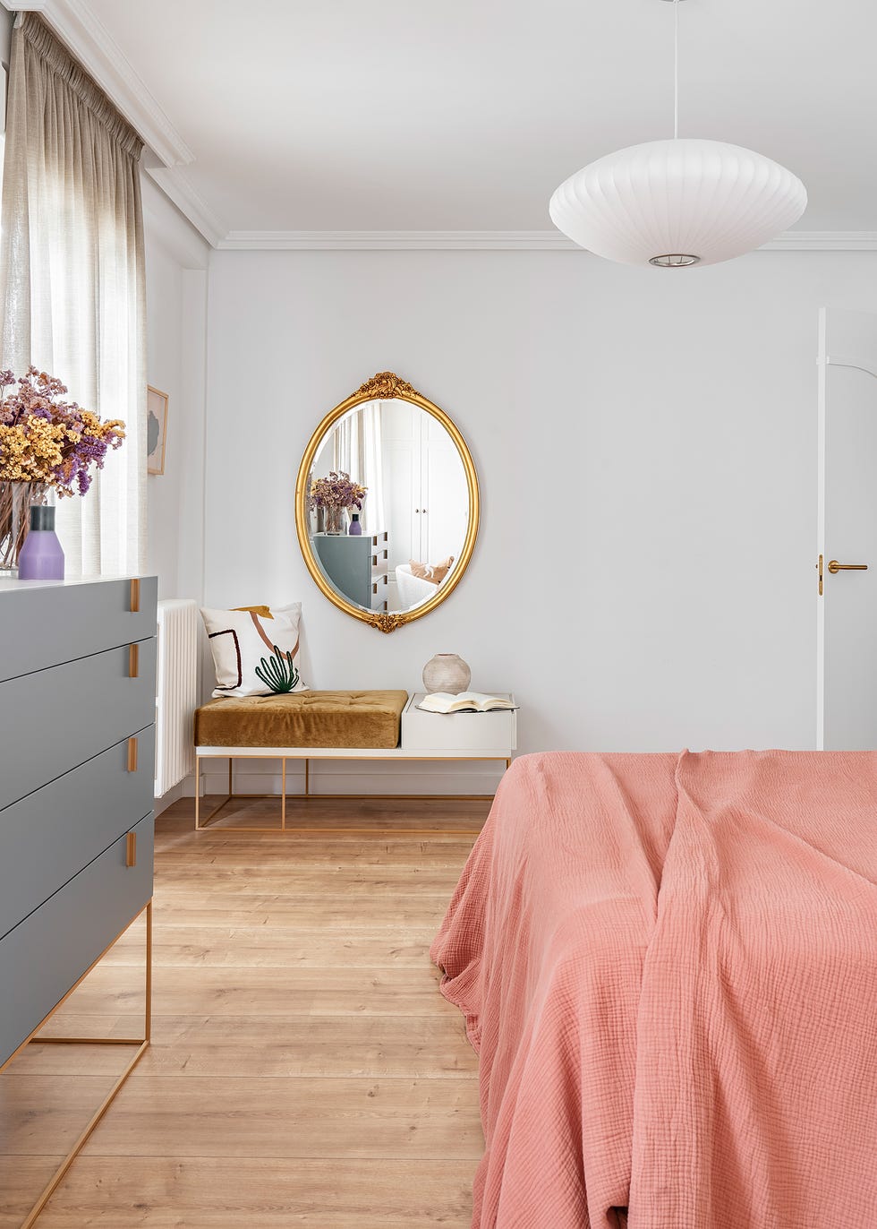 dormitorio con espejo de pared antiguo dorado y textiles rosas
