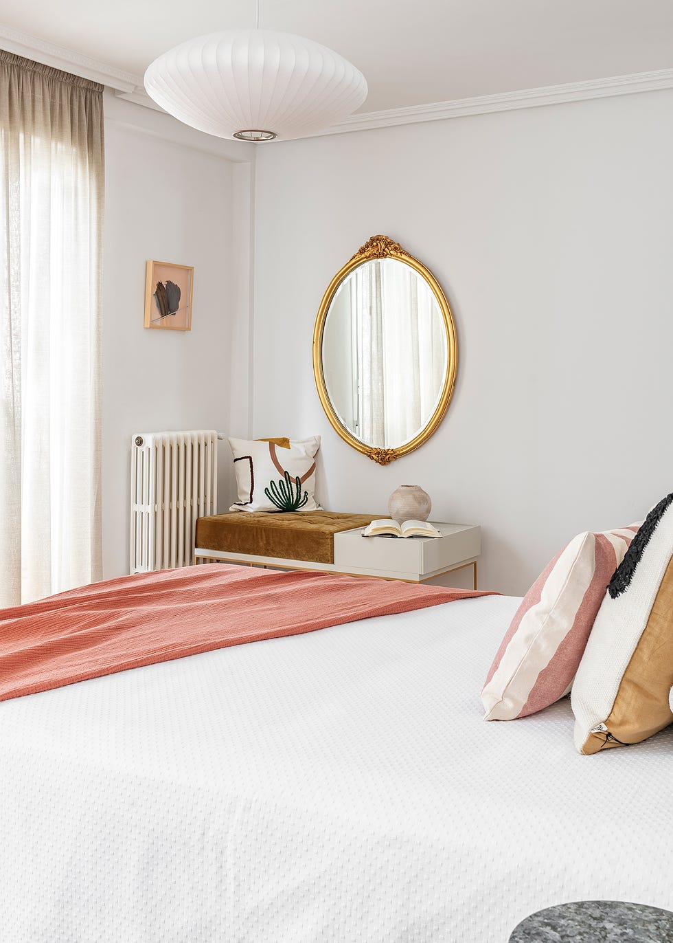dormitorio con espejo de pared antiguo dorado y textiles rosas