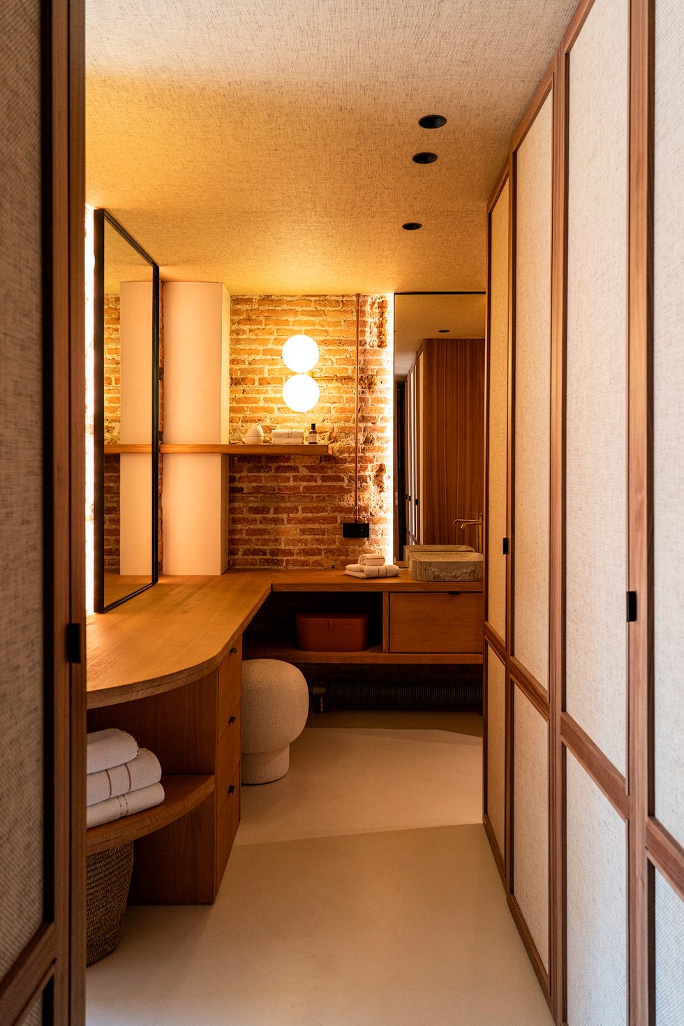 baño con mueble de madera y pared de ladrillo visto