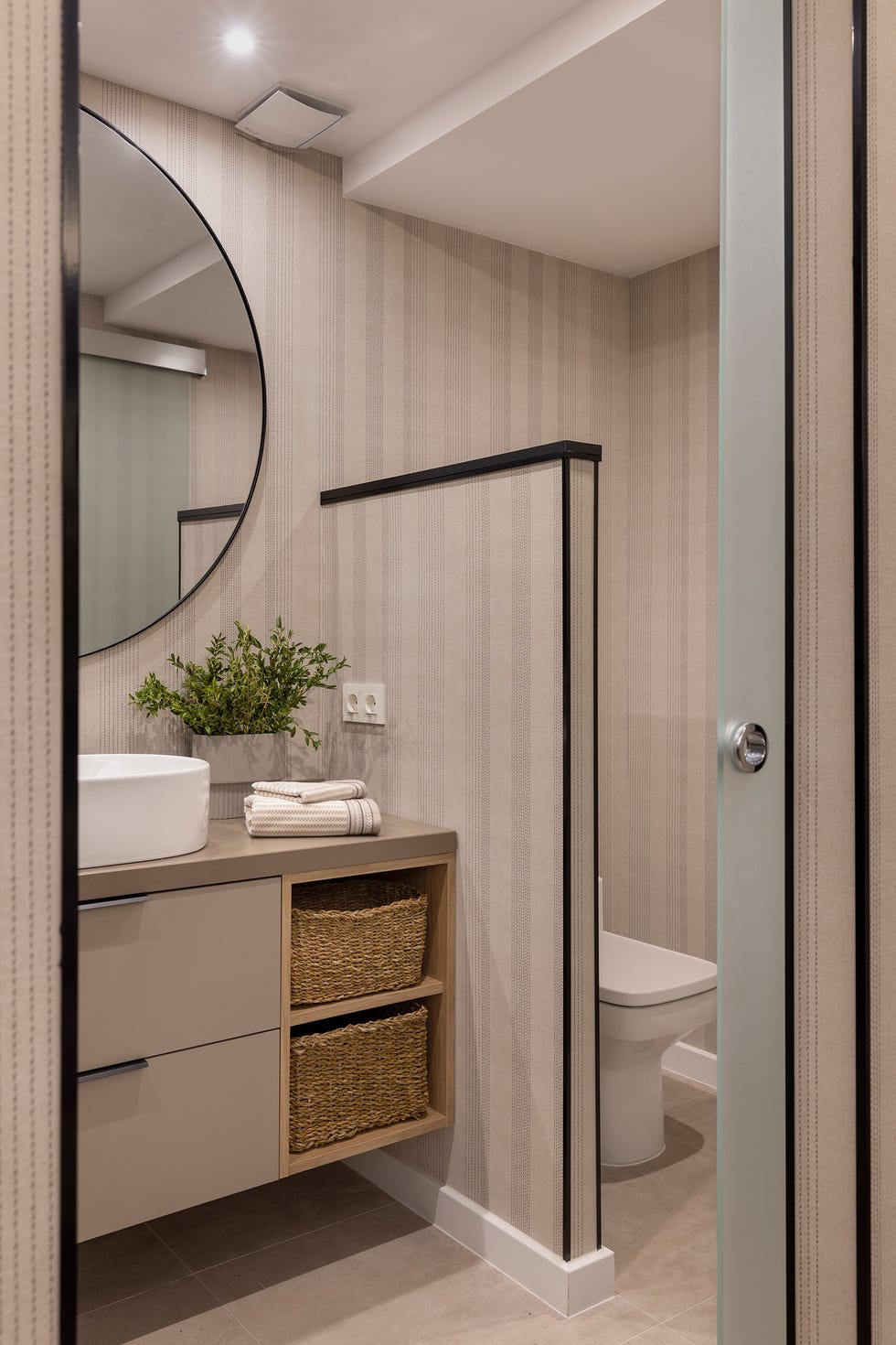 baño con mueble volado en color topo y papel pintado a rayas