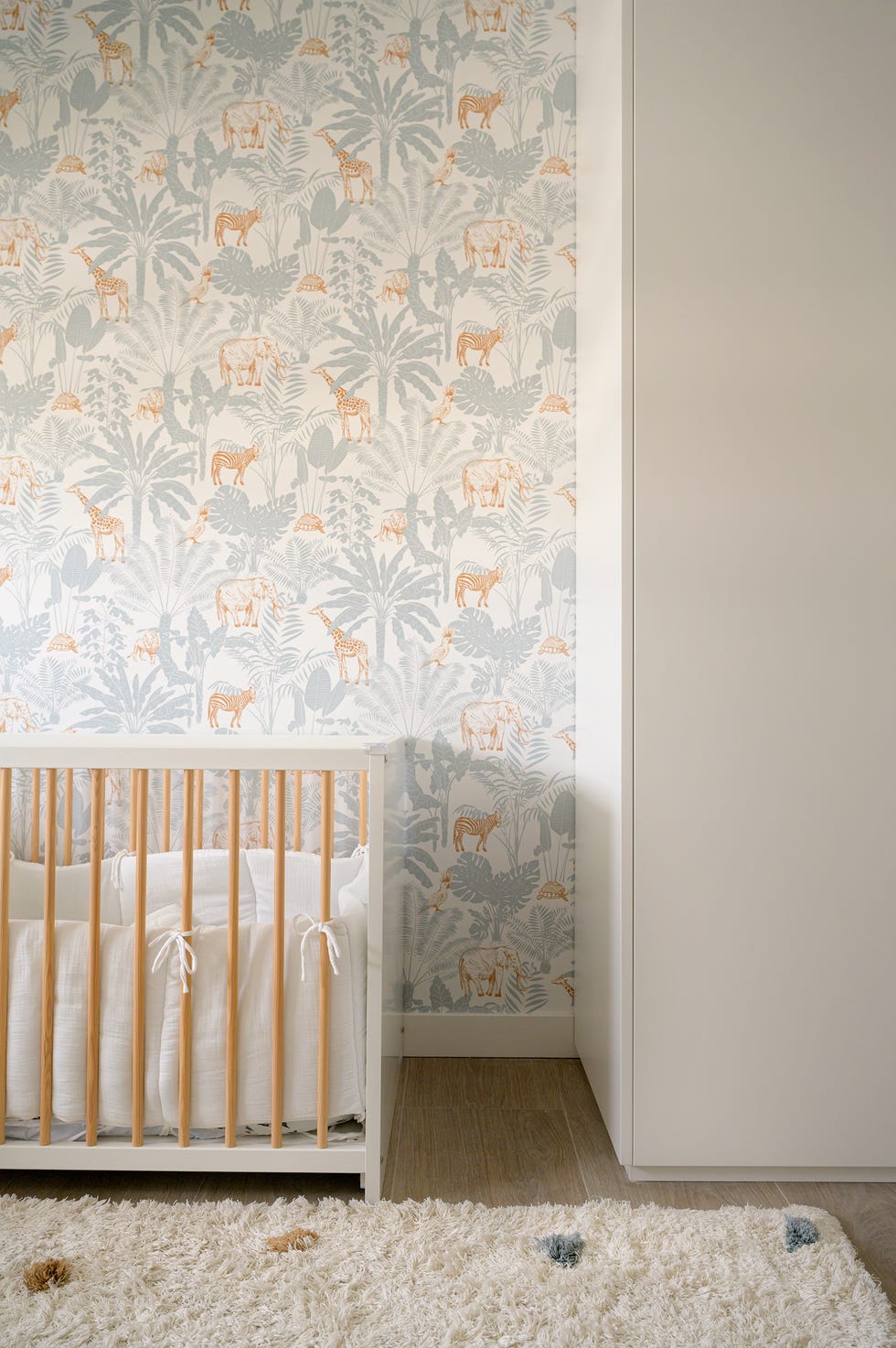 dormitorio infantil con cuna y papel pintado con dibujos de animales