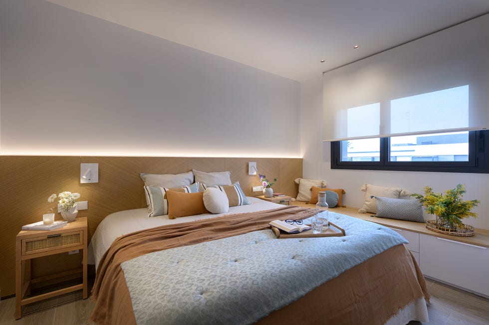 dormitorio con cabecero de madera y banco con almacenaje bajo la ventana